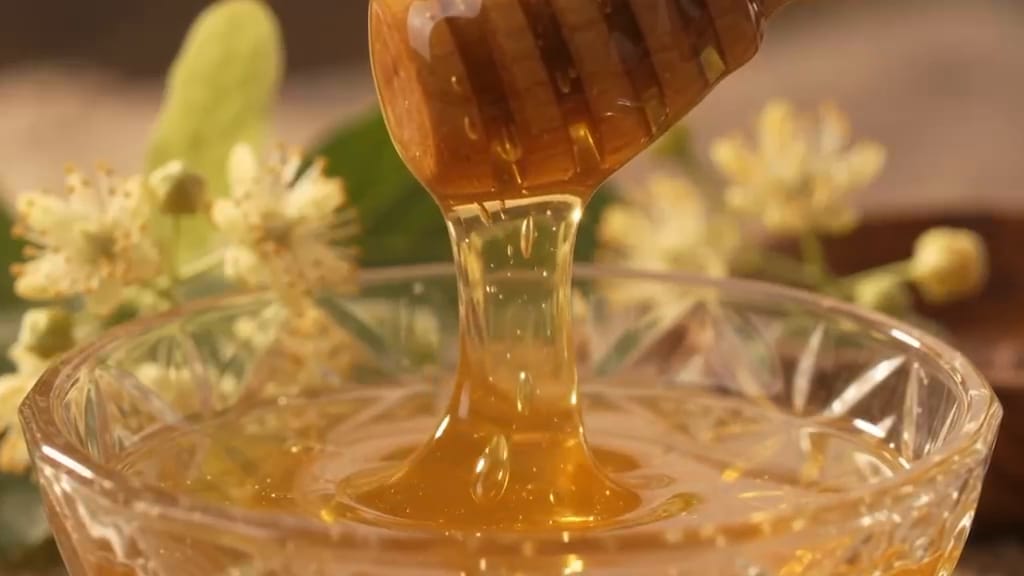 Ahşap kaşıktan kristal kaseye akan ıhlamur balı